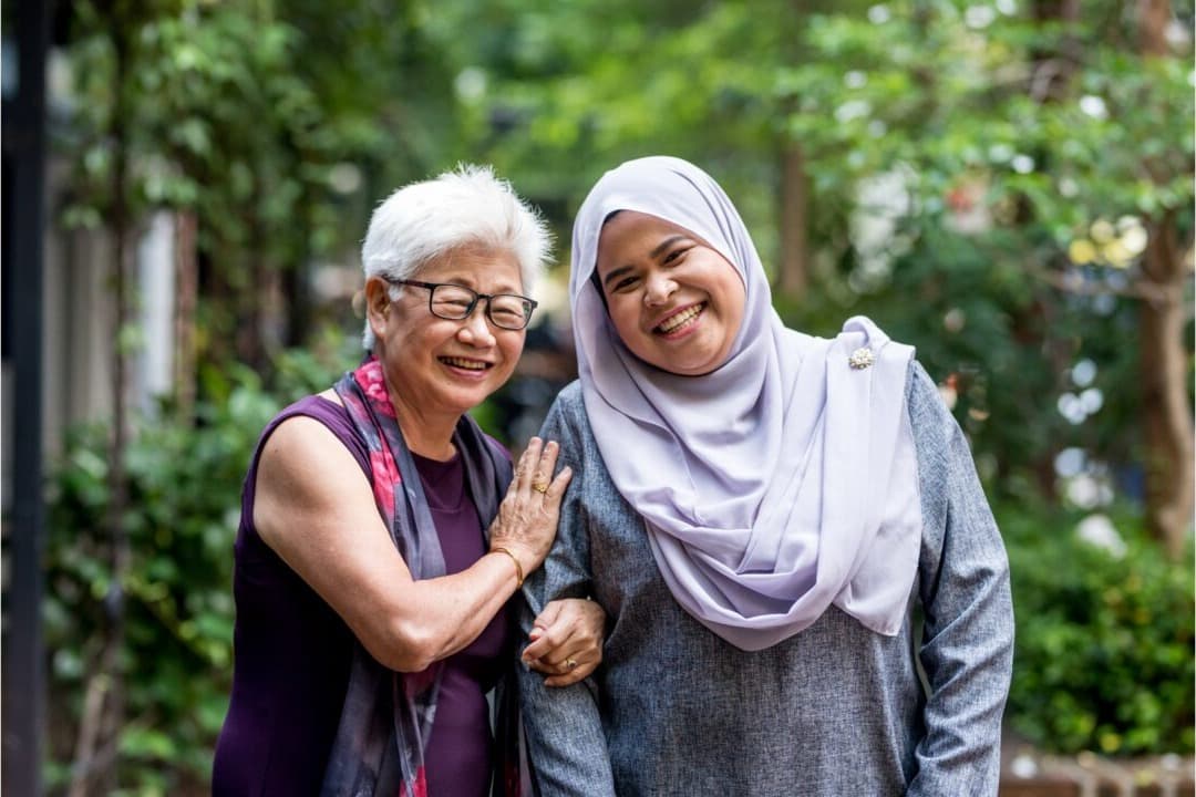 A carer talking warmly with an elderly client at their kitchen table