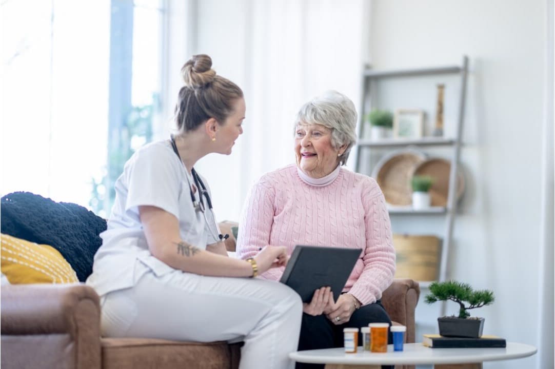 A care worker sitting beside an older man at home, going through a care plan
